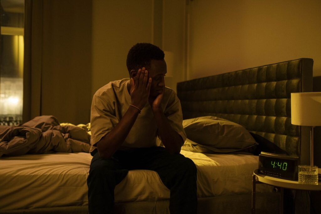 Man sitting on the edge of his bed in the middle of the night, unable to sleep